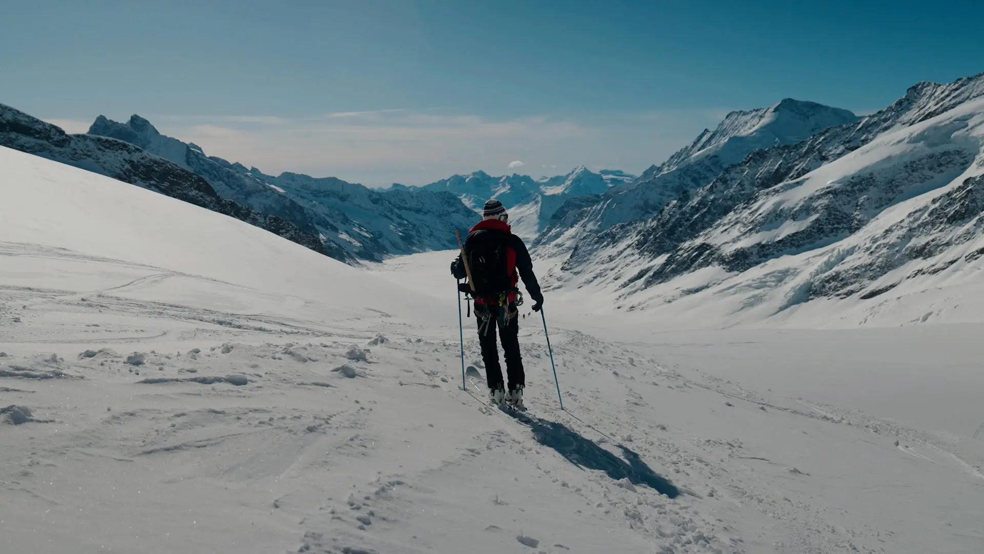 Bergführer mit Skiern und Stöcken im verschneiten Hochgebirge, Blick ins Tal.