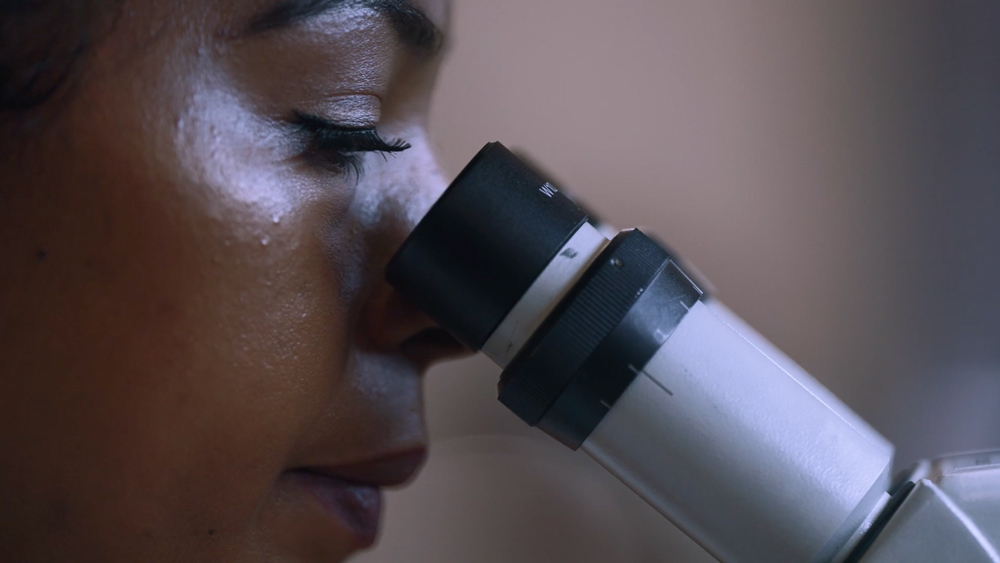 Mitarbeiterin prüft Bauteile am Mikroskop in der Elektronikfertigung bei VarioSystems.