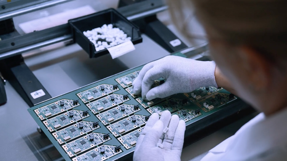 Handschuhe platzieren Bauteile auf Leiterplatten in der Produktion bei VarioSystems.