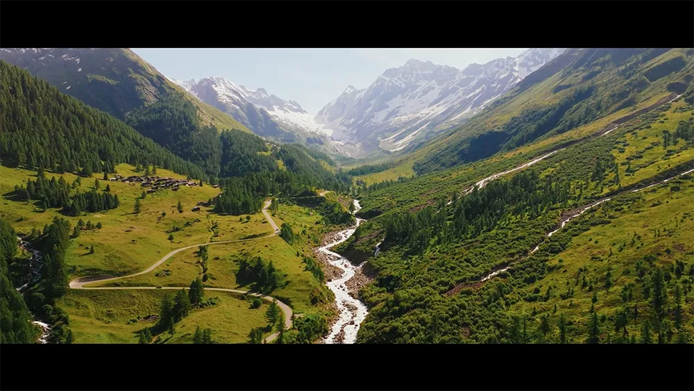 Weites alpines Tal mit Flusslauf und Bergen – Landschaftsaufnahme aus dem Imagefilm von BLS