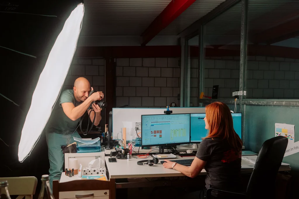 Fotograf bei der Arbeit im Gespräch mit einer Mitarbeiterin während eines Unternehmensporträts.