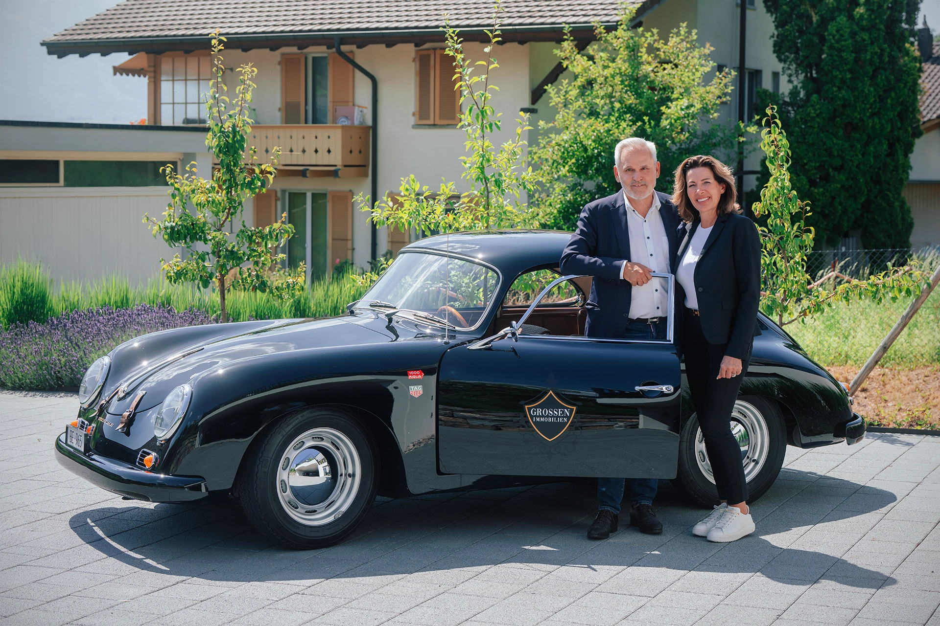 Urs Grossen und Nathalie Fink vor einem Porsche 356 mit Grossen-Immobilien-Logo